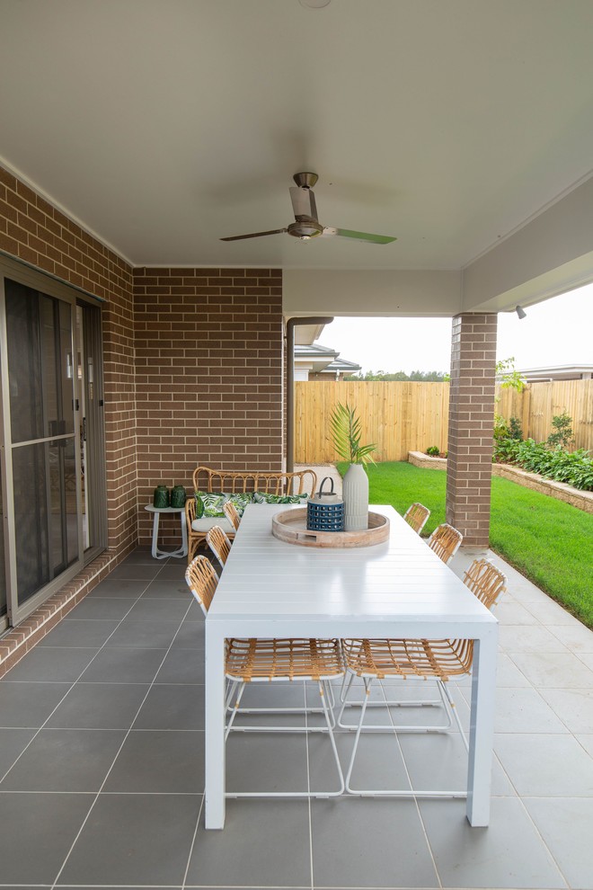 Photo of a mid-sized beach style backyard patio in Brisbane with tile and a roof extension.