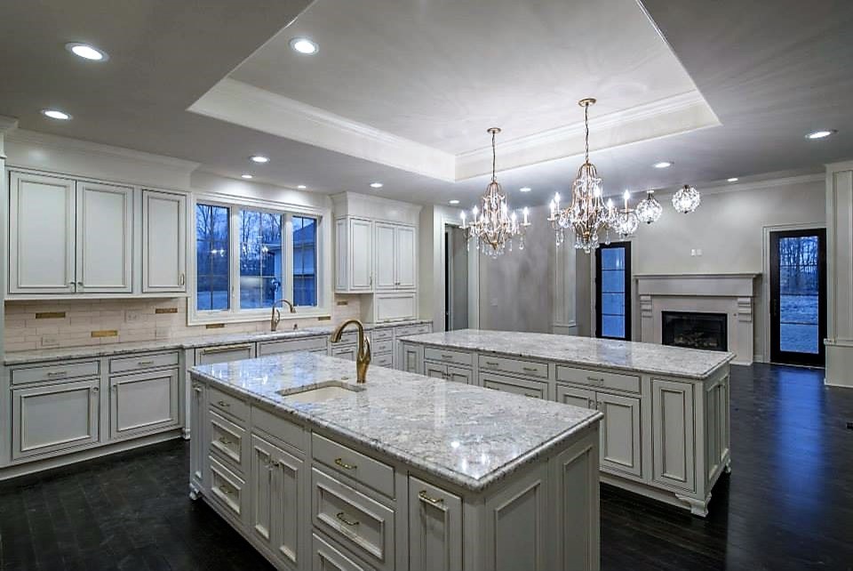 Inspiration for a large transitional u-shaped dark wood floor eat-in kitchen remodel in Columbus with a single-bowl sink, raised-panel cabinets, white cabinets, granite countertops, metallic backsplash, porcelain backsplash and two islands