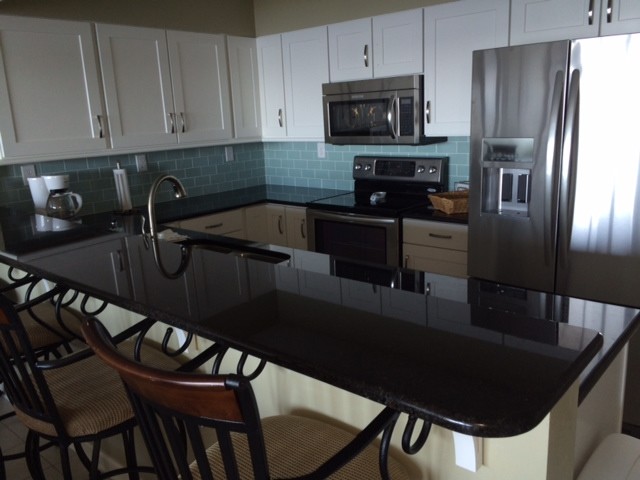 Inspiration for a transitional u-shaped kitchen remodel with an undermount sink, shaker cabinets, white cabinets, granite countertops, blue backsplash, subway tile backsplash and stainless steel appliances