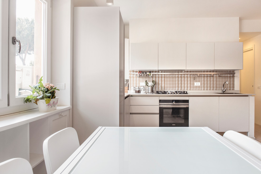 This is an example of a mid-sized contemporary l-shaped open plan kitchen in Rome with an integrated sink, flat-panel cabinets, white cabinets, quartzite benchtops, porcelain splashback, stainless steel appliances, no island, multi-coloured splashback, medium hardwood floors and brown floor.