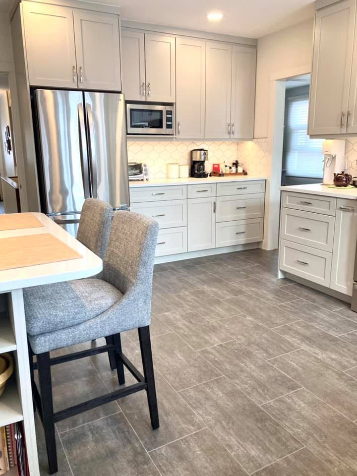 Inspiration for a mid-sized transitional u-shaped vinyl floor and gray floor enclosed kitchen remodel with an undermount sink, shaker cabinets, beige cabinets, quartz countertops, white backsplash, ceramic backsplash, stainless steel appliances and white countertops