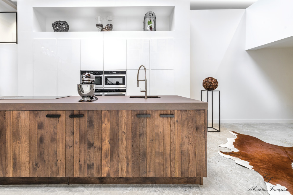 Cette image montre une grande cuisine ouverte design en bois brun avec un placard à porte plane, un plan de travail en quartz, sol en béton ciré, îlot et un plan de travail marron.