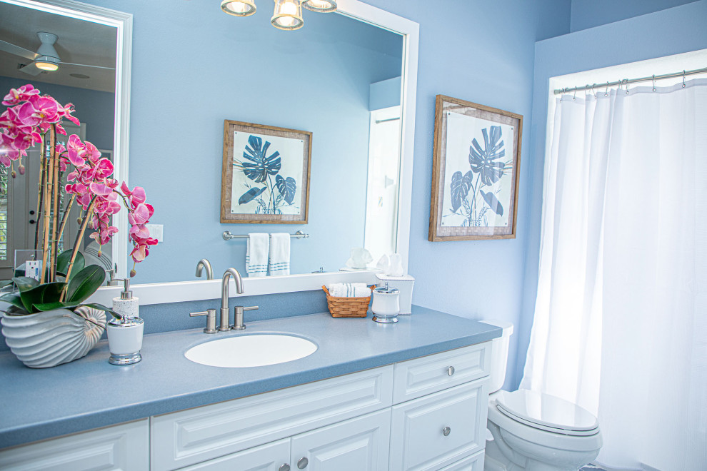 Стильный дизайн: главная ванная комната среднего размера в современном стиле с фасадами в стиле шейкер, белыми фасадами, угловой ванной, душем над ванной, унитазом-моноблоком, синими стенами, подвесной раковиной, синей столешницей, тумбой под одну раковину и встроенной тумбой - последний тренд