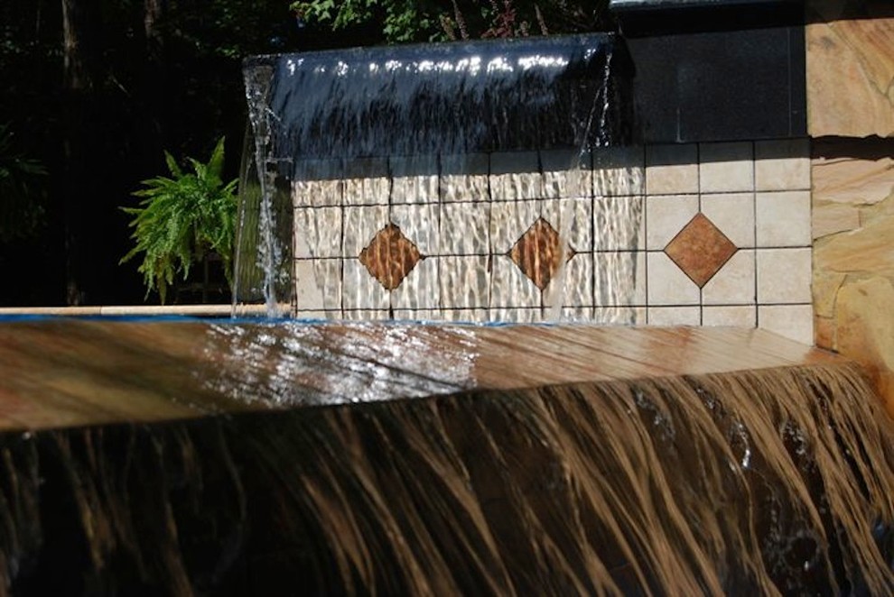 Example of a mid-sized backyard stone and rectangular natural pool fountain design