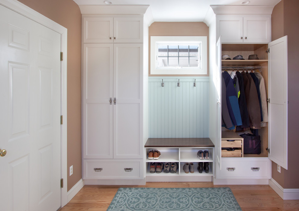 Photo of a small transitional mudroom in New York with brown walls, medium hardwood floors, a white front door and blue floor.