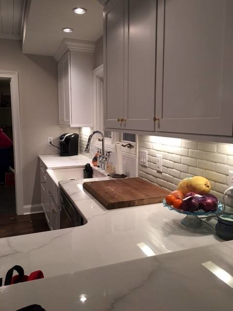 Transitional kitchen in Raleigh with a farmhouse sink, white cabinets, marble benchtops, white splashback, stone slab splashback and with island.
