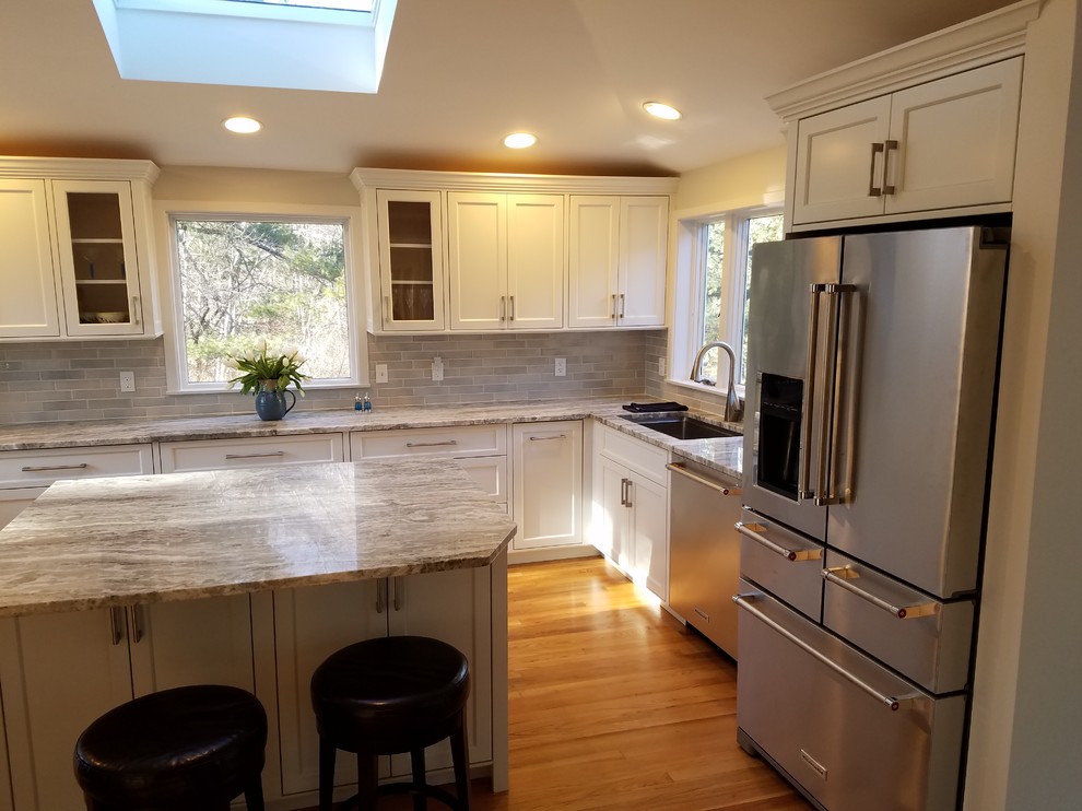 Example of a large transitional u-shaped medium tone wood floor eat-in kitchen design in Boston with a single-bowl sink, recessed-panel cabinets, white cabinets, granite countertops, gray backsplash, ceramic backsplash, stainless steel appliances and an island
