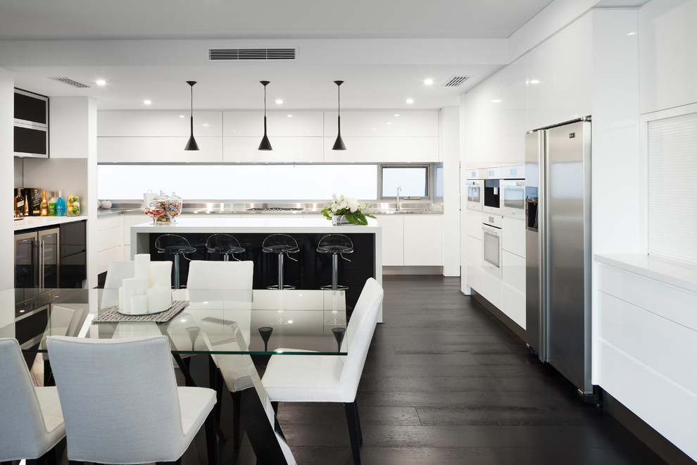 This is an example of a modern eat-in kitchen in Perth with flat-panel cabinets, white cabinets, quartz benchtops, metallic splashback, glass sheet splashback, with island and white benchtop.