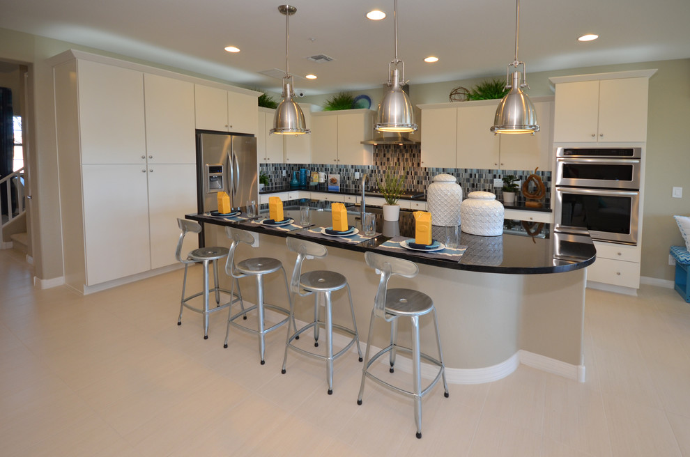 Expansive modern l-shaped open plan kitchen in Phoenix with an undermount sink, flat-panel cabinets, white cabinets, quartz benchtops, blue splashback, mosaic tile splashback, stainless steel appliances, porcelain floors and with island.
