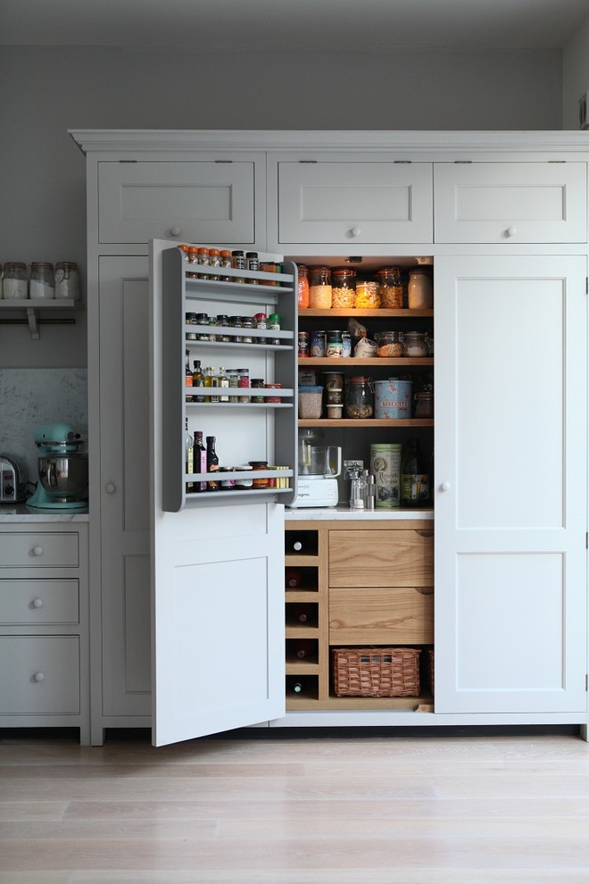 Design ideas for a mid-sized traditional single-wall kitchen pantry in London with shaker cabinets, grey cabinets, marble benchtops, grey splashback, stone slab splashback, light hardwood floors and with island.