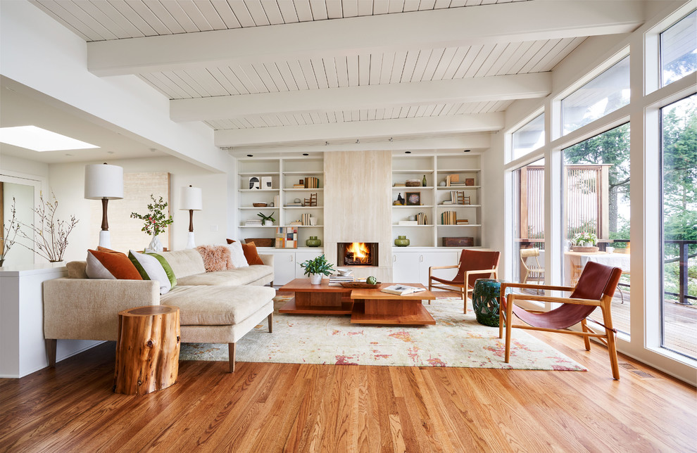 Example of a large trendy open concept medium tone wood floor and brown floor living room library design in Portland with white walls and a standard fireplace