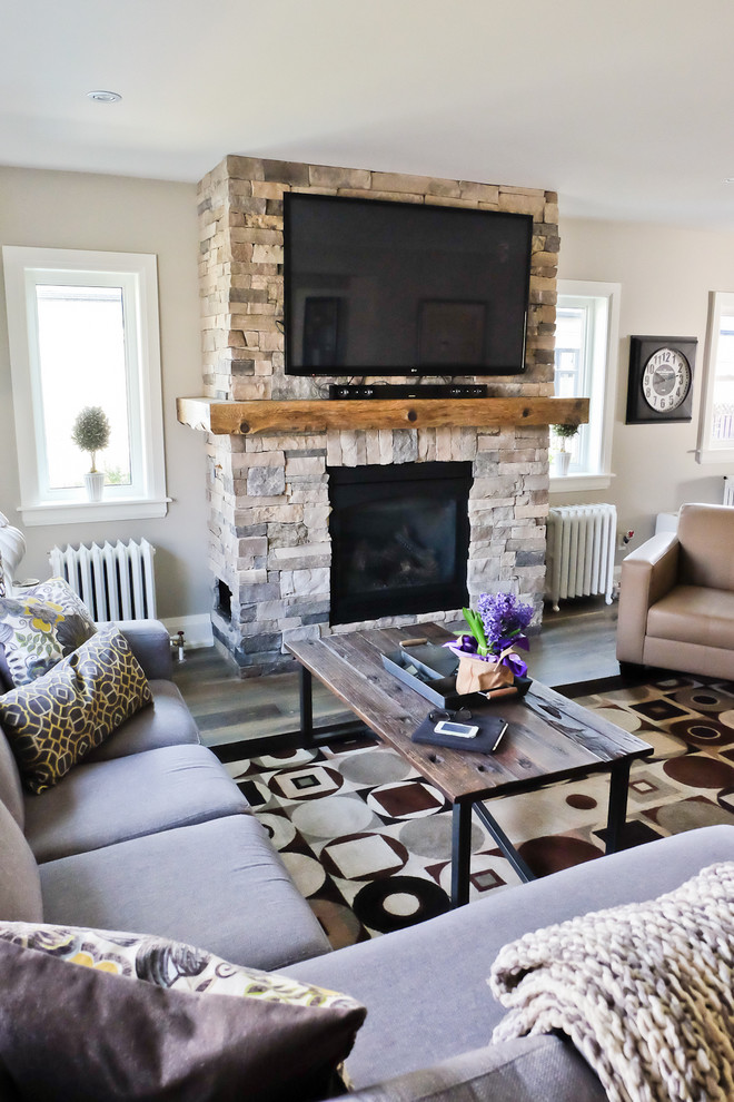 Photo of a mid-sized transitional open concept family room in Toronto with beige walls, medium hardwood floors, a standard fireplace, a stone fireplace surround and a wall-mounted tv.