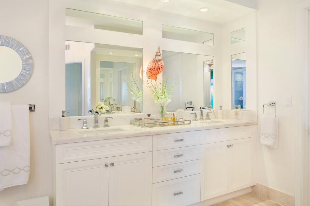 Mid-sized master bathroom in Miami with raised-panel cabinets, white cabinets, a freestanding tub, an alcove shower, a one-piece toilet, white tile, porcelain tile, beige walls, porcelain floors, an undermount sink, marble benchtops, beige floor, a hinged shower door and beige benchtops.