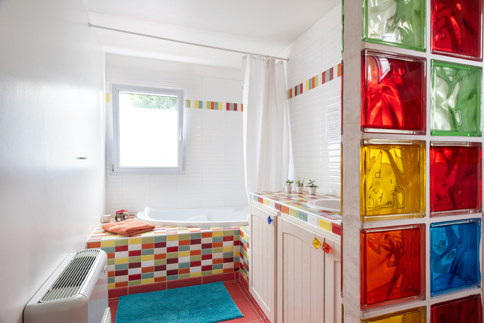 Mid-sized contemporary kids bathroom in Paris with a corner tub, a wall-mount toilet, multi-coloured tile, subway tile, white walls, an undermount sink, tile benchtops, pink floor and multi-coloured benchtops.