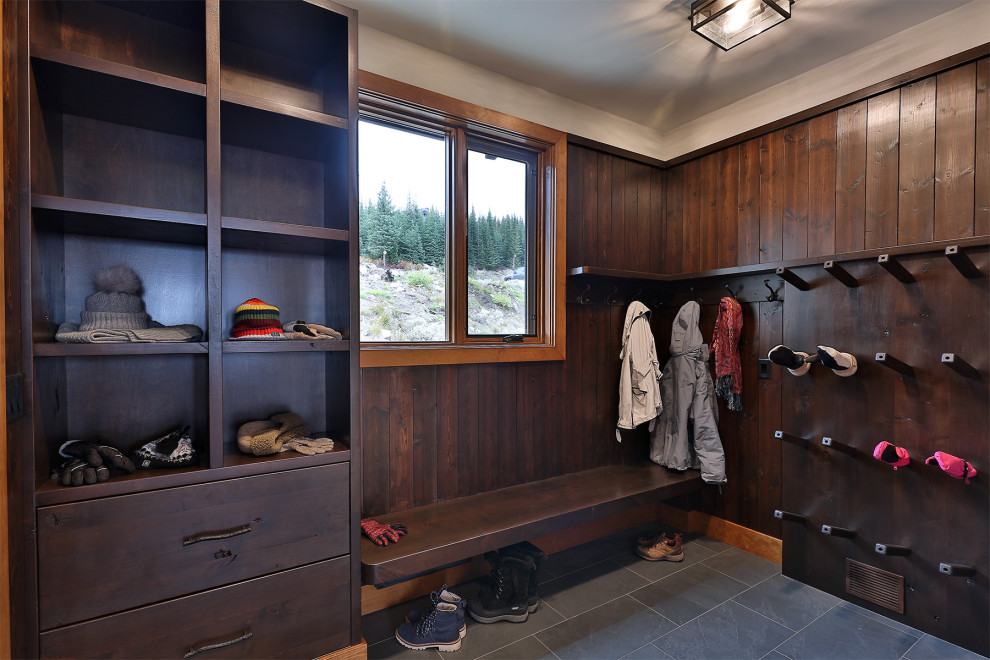 Example of a mountain style ceramic tile, gray floor and wood wall mudroom design with brown walls and a dark wood front door