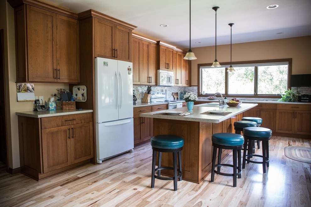 Eat-in kitchen - large transitional l-shaped light wood floor eat-in kitchen idea in Cedar Rapids with recessed-panel cabinets, medium tone wood cabinets, laminate countertops, multicolored backsplash, mosaic tile backsplash, white appliances, an island and a double-bowl sink