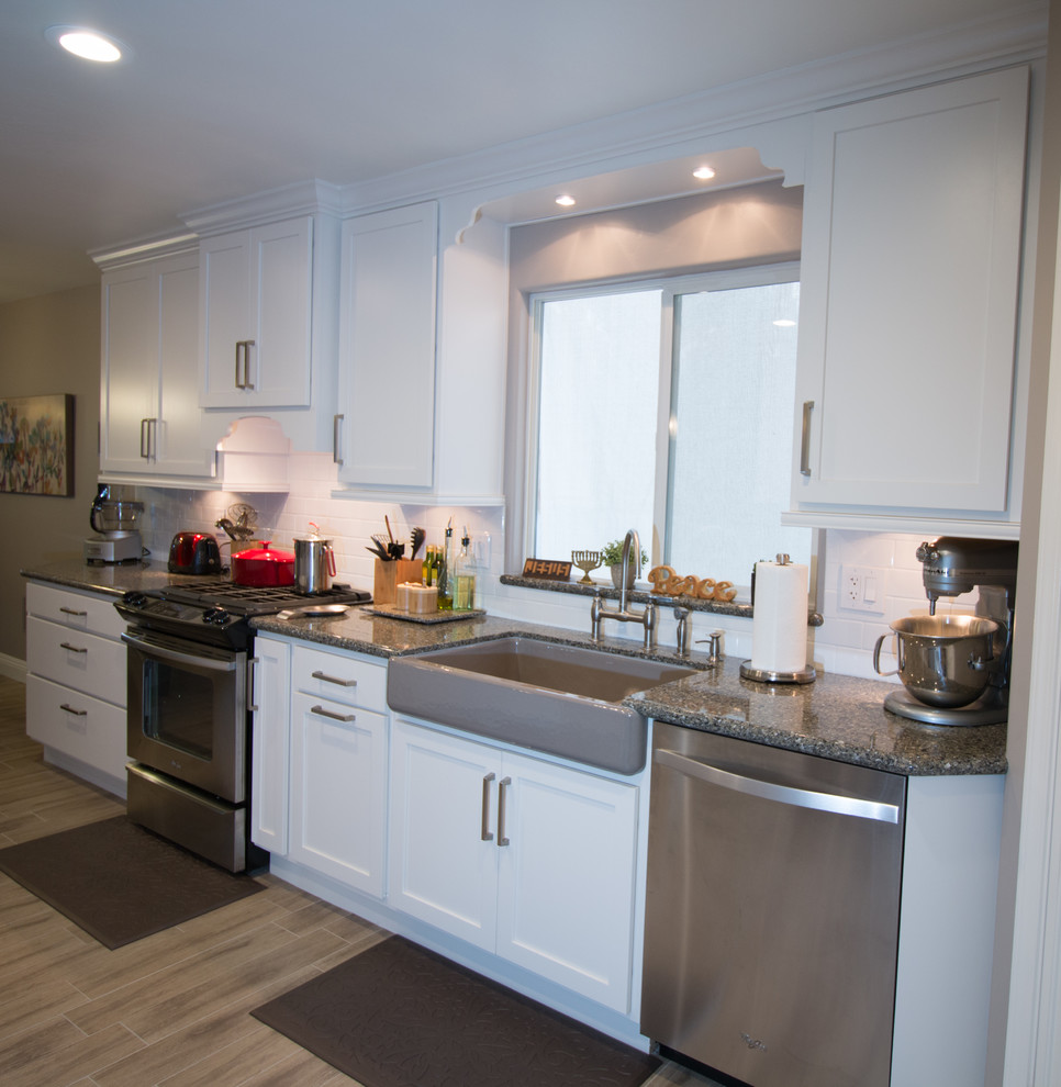 Open concept kitchen - mid-sized transitional galley porcelain tile open concept kitchen idea with a farmhouse sink, shaker cabinets, white cabinets, quartz countertops, white backsplash, subway tile backsplash and stainless steel appliances