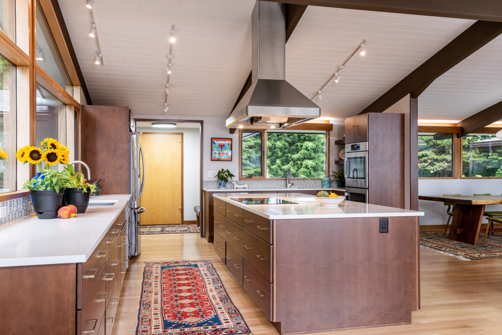 Inspiration for a mid-sized 1960s light wood floor, beige floor and exposed beam open concept kitchen remodel in Other with an undermount sink, flat-panel cabinets, brown cabinets, quartz countertops, green backsplash, mosaic tile backsplash, stainless steel appliances, an island and white countertops