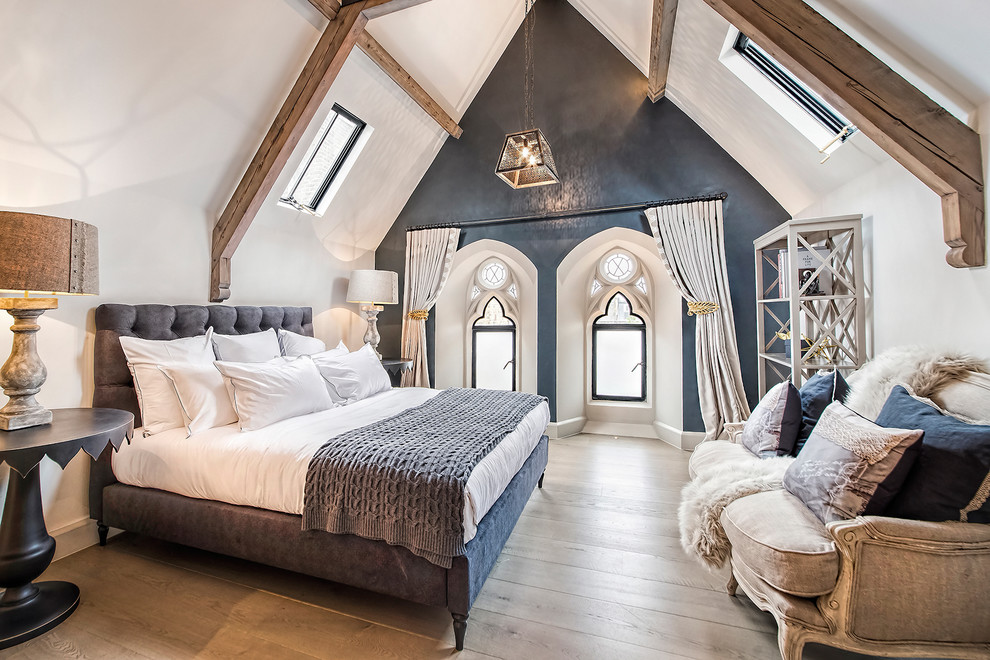 Photo of a large master bedroom in London with blue walls and light hardwood floors.