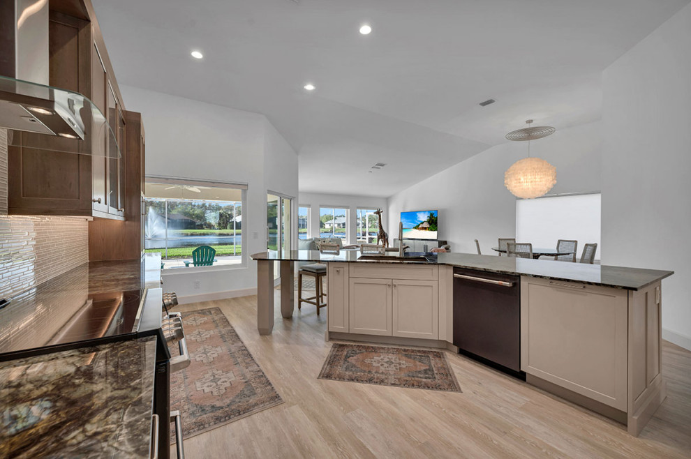 Example of a huge trendy single-wall vinyl floor and beige floor open concept kitchen design in Miami with an undermount sink, shaker cabinets, medium tone wood cabinets, quartzite countertops, beige backsplash, glass sheet backsplash, black appliances, an island and multicolored countertops