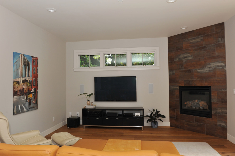 This is an example of a mid-sized contemporary formal open concept living room in San Francisco with grey walls, light hardwood floors, a corner fireplace, a tile fireplace surround and a freestanding tv.