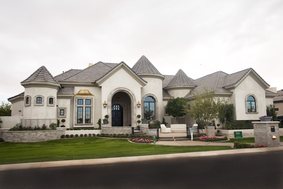 Large transitional two-storey concrete beige house exterior in Phoenix with a gable roof and a tile roof.