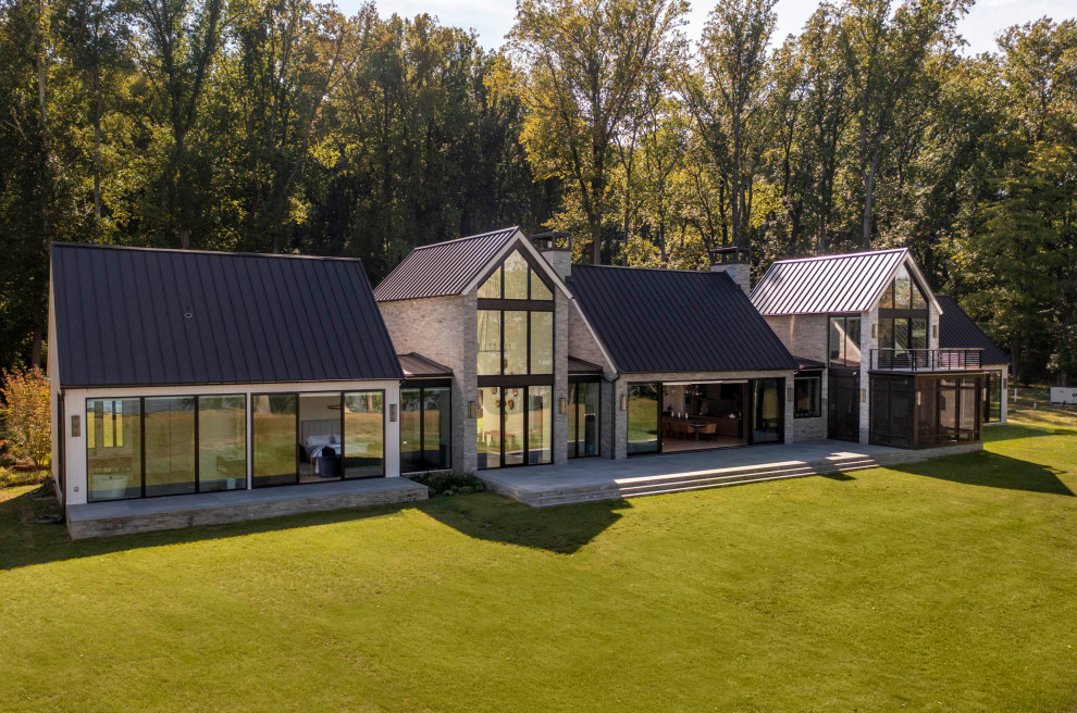 Inspiration pour une très grande façade de maison grise minimaliste en pierre à un étage avec un toit en métal et un toit marron.