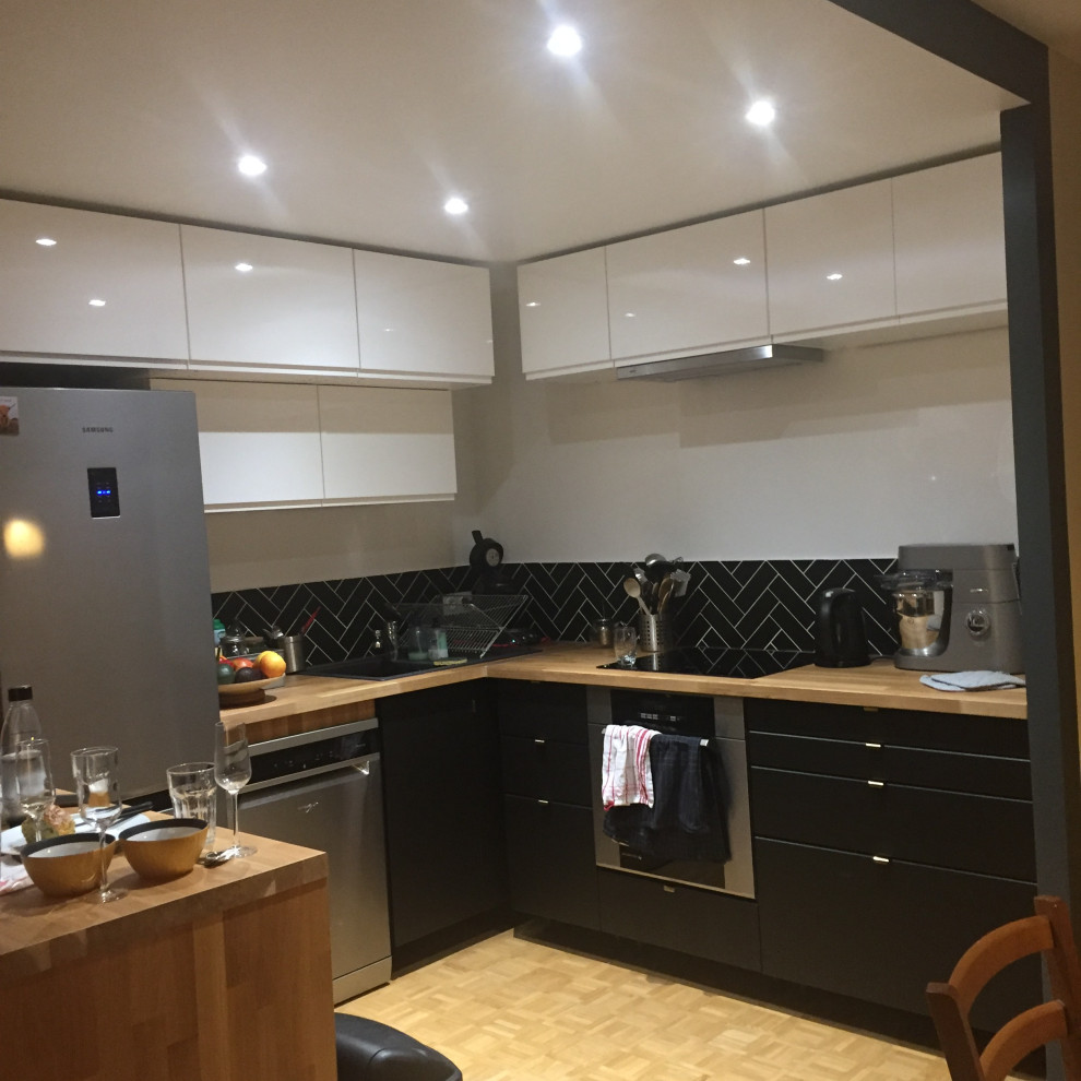Idées déco pour une cuisine ouverte contemporaine en U de taille moyenne avec un évier 1 bac, des portes de placard noires, un plan de travail en bois, une crédence noire, une crédence en céramique, un électroménager en acier inoxydable et parquet clair.