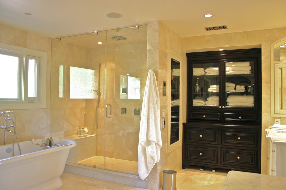 This is an example of a large traditional master bathroom in Orange County with black cabinets, a freestanding tub, beige tile, marble, beige walls, marble floors, wood benchtops, raised-panel cabinets, a corner shower, a one-piece toilet, an undermount sink, beige floor and a hinged shower door.