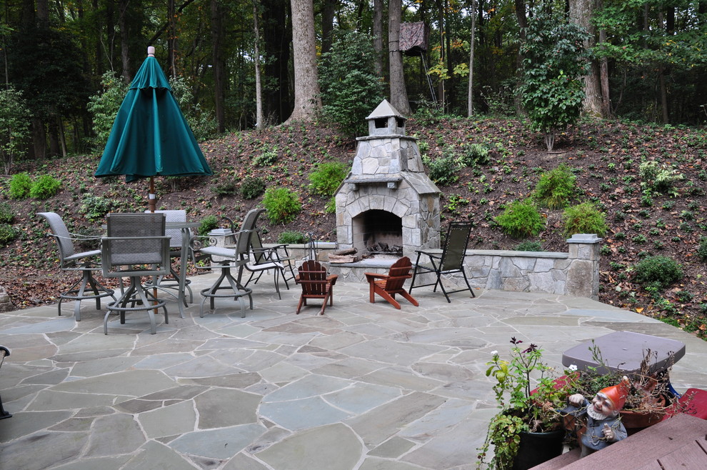 This is an example of a large traditional backyard patio in DC Metro with a fire feature, natural stone pavers and no cover.