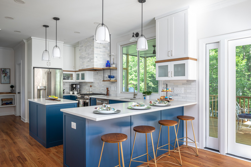 Design ideas for a mid-sized transitional l-shaped eat-in kitchen in Raleigh with an undermount sink, shaker cabinets, blue cabinets, quartzite benchtops, white splashback, marble splashback, stainless steel appliances, medium hardwood floors, with island, brown floor and white benchtop.