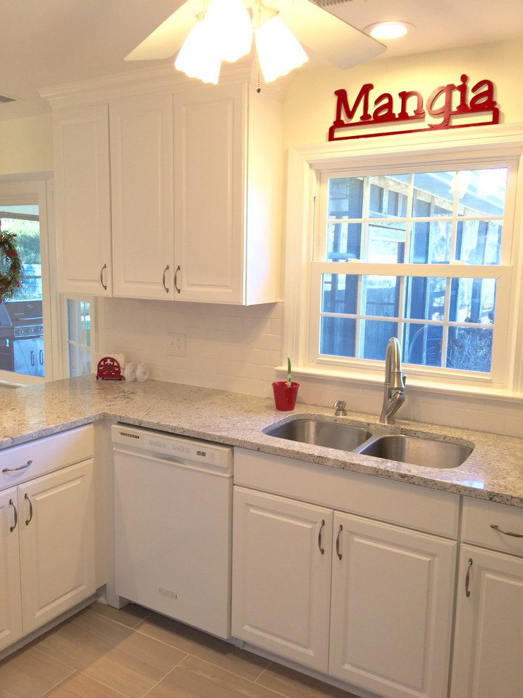 Example of a mid-sized transitional u-shaped porcelain tile enclosed kitchen design with an undermount sink, raised-panel cabinets, white cabinets, granite countertops, white backsplash, subway tile backsplash, stainless steel appliances and a peninsula