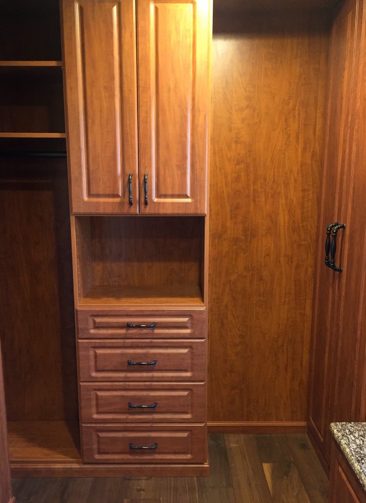 Large traditional women's walk-in wardrobe in Columbus with raised-panel cabinets, medium wood cabinets and dark hardwood floors.