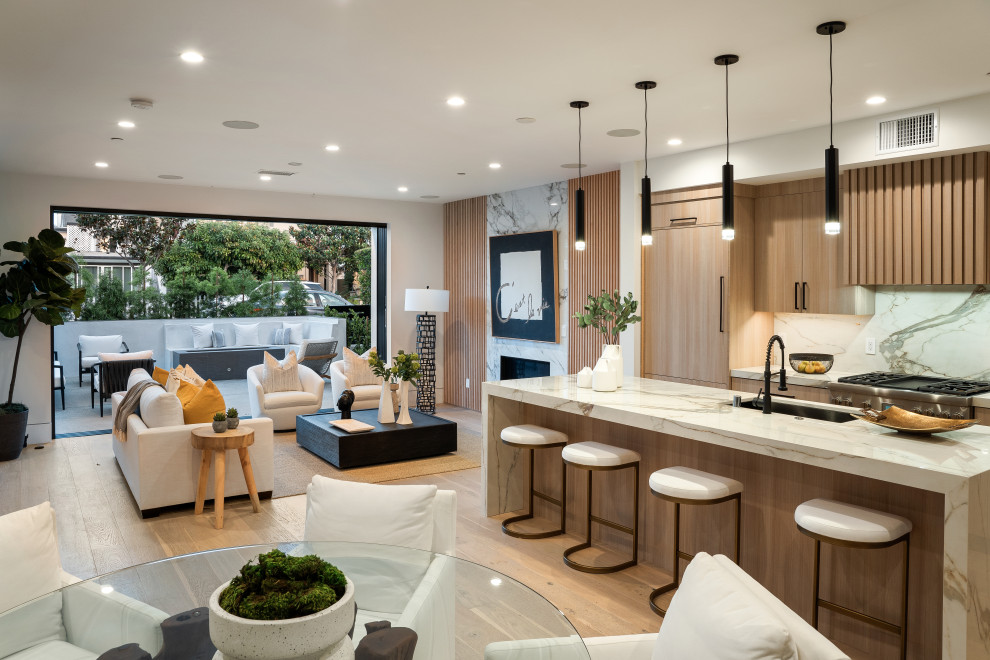 Inspiration for an expansive contemporary galley open plan kitchen in Los Angeles with an island, a submerged sink, flat-panel cabinets, light wood cabinets, integrated appliances, light hardwood flooring, beige floors and beige worktops.