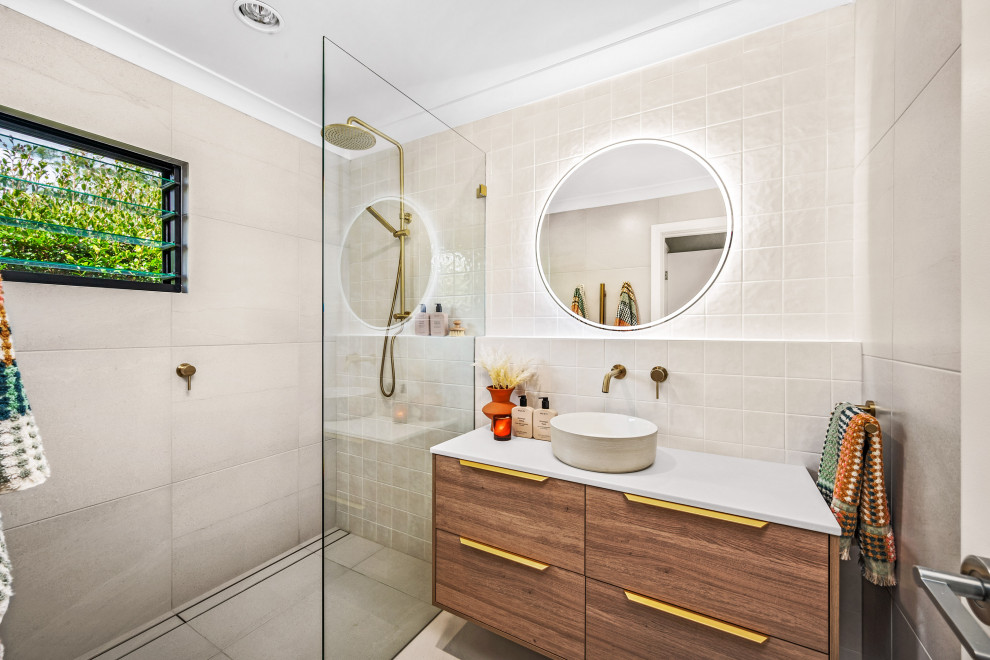 This is an example of a mid-sized beach style 3/4 bathroom in Central Coast with flat-panel cabinets, medium wood cabinets, an open shower, a two-piece toilet, beige tile, beige walls, a vessel sink, beige floor, an open shower, white benchtops, a single vanity and a floating vanity.