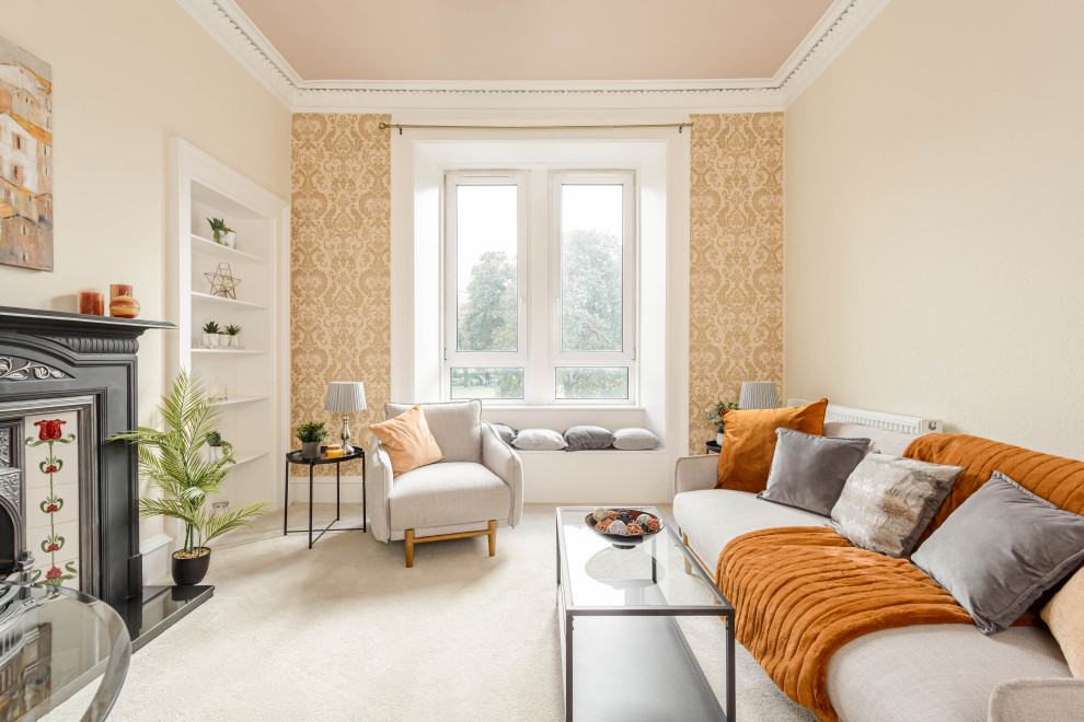 Cette image montre un salon traditionnel avec un mur beige, moquette, une cheminée standard, un manteau de cheminée en carrelage, un sol beige et du papier peint.