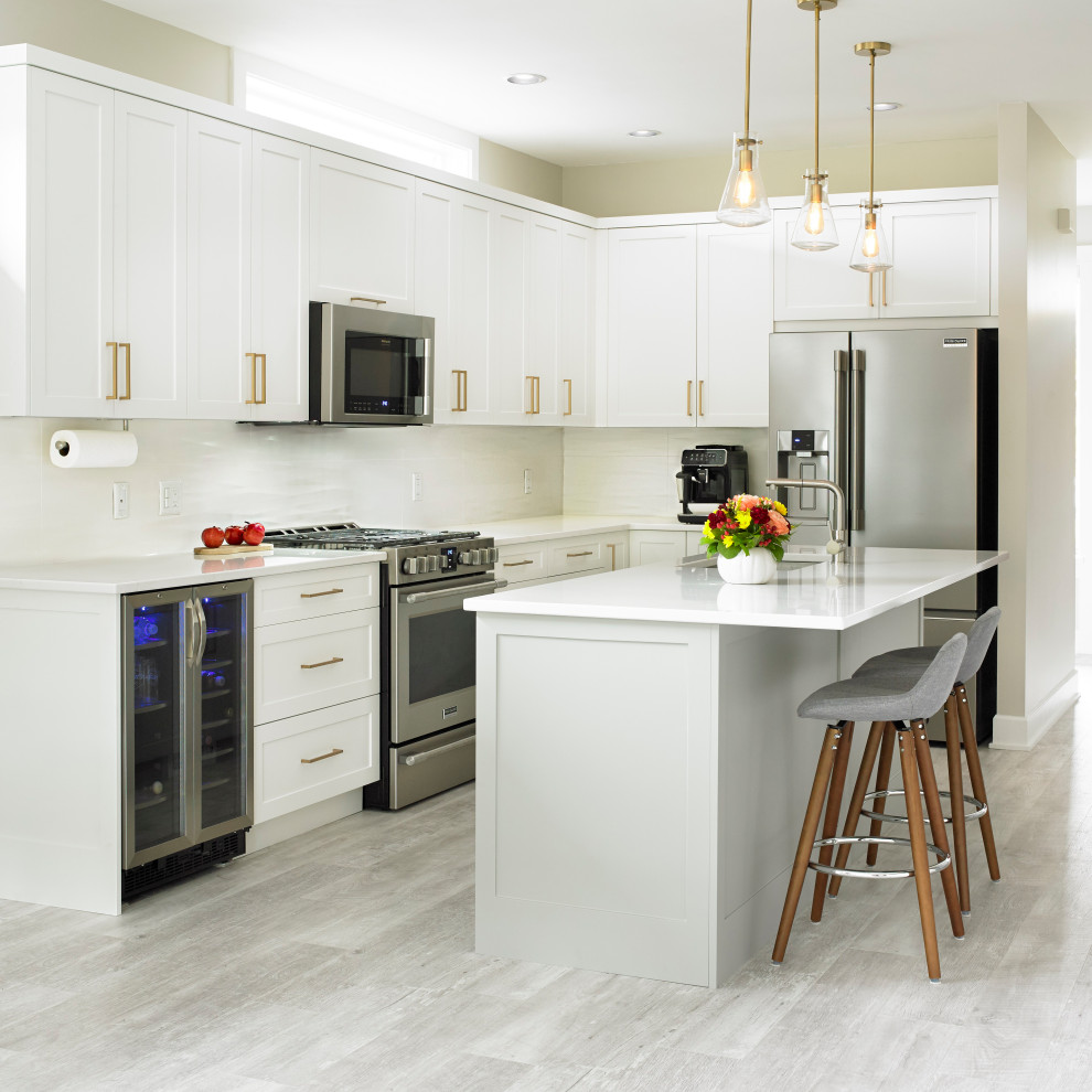 Mid-sized transitional l-shaped beige floor open concept kitchen photo with an undermount sink, shaker cabinets, white cabinets, quartz countertops, white backsplash, ceramic backsplash, stainless steel appliances and an island