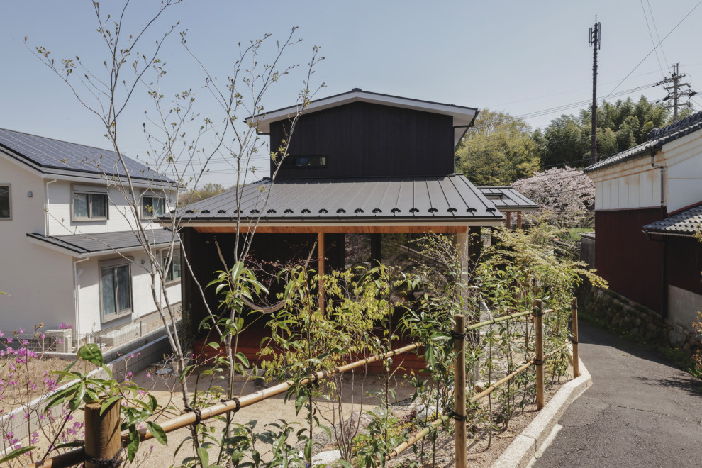 Imagen de fachada de casa negra y negra de tamaño medio de dos plantas con revestimiento de madera, tejado a dos aguas, tejado de metal y panel y listón