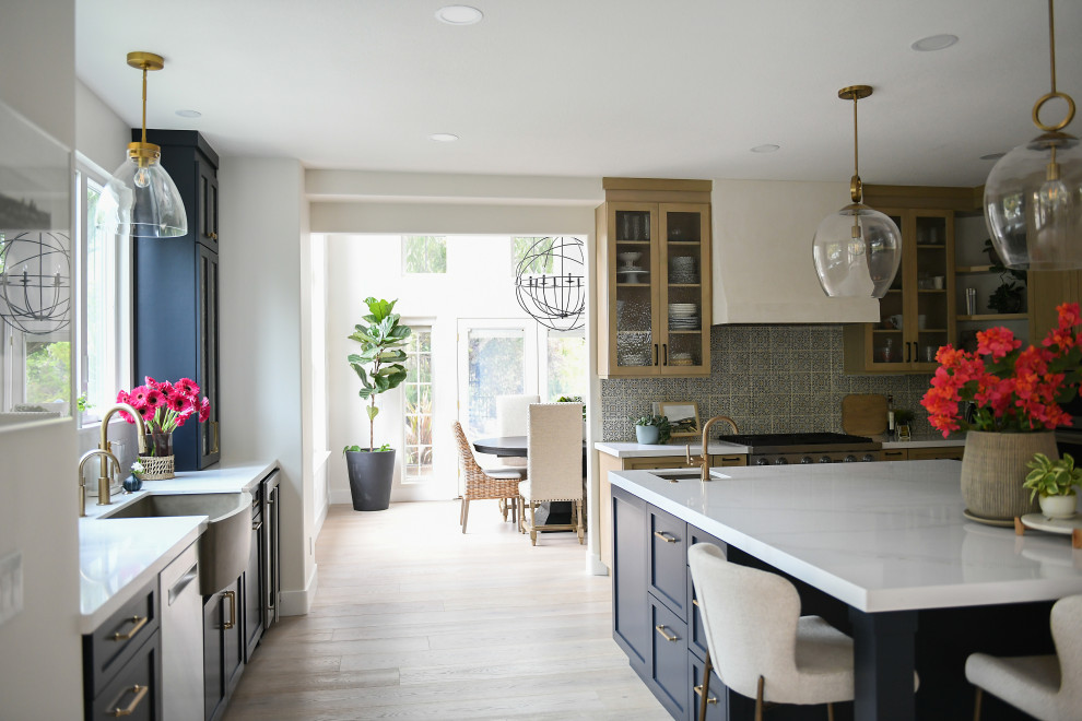 Kitchen - large mediterranean medium tone wood floor and brown floor kitchen idea in San Diego with a farmhouse sink, shaker cabinets, light wood cabinets, quartz countertops, blue backsplash, terra-cotta backsplash, paneled appliances, an island and white countertops