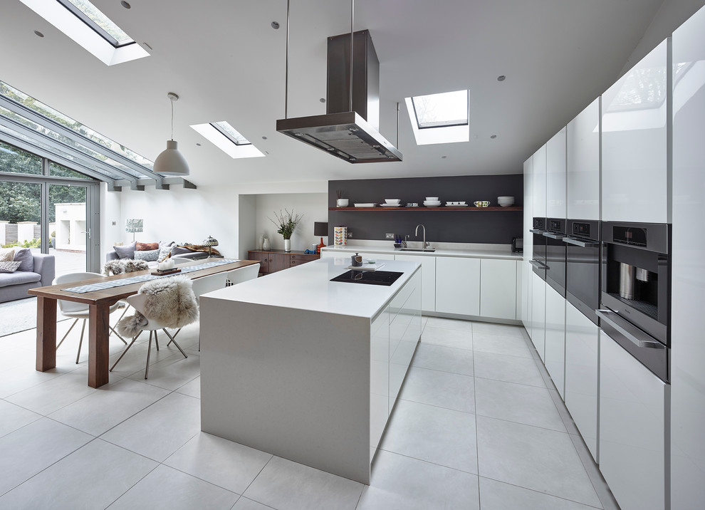 This is an example of a large modern l-shaped open plan kitchen in Other with a drop-in sink, flat-panel cabinets, white cabinets, quartzite benchtops, stainless steel appliances, porcelain floors, with island, white floor, grey splashback and white benchtop.
