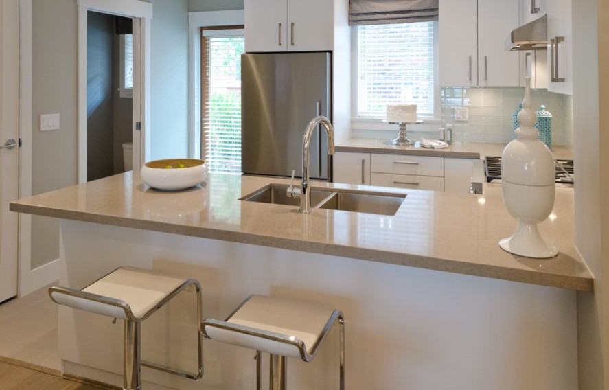 Photo of a small contemporary u-shaped open plan kitchen in Dallas with a double-bowl sink, flat-panel cabinets, white cabinets, white splashback, glass tile splashback, stainless steel appliances and a peninsula.