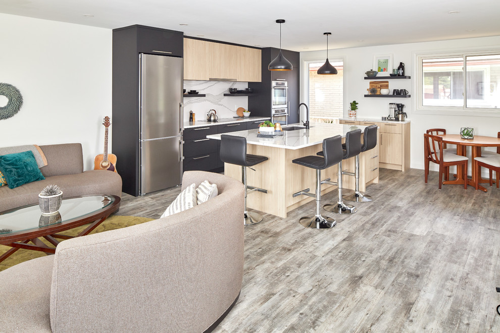 Photo of a mid-sized modern single-wall eat-in kitchen in Toronto with a triple-bowl sink, flat-panel cabinets, black cabinets, quartz benchtops, white splashback, stainless steel appliances, medium hardwood floors, with island, grey floor and white benchtop.
