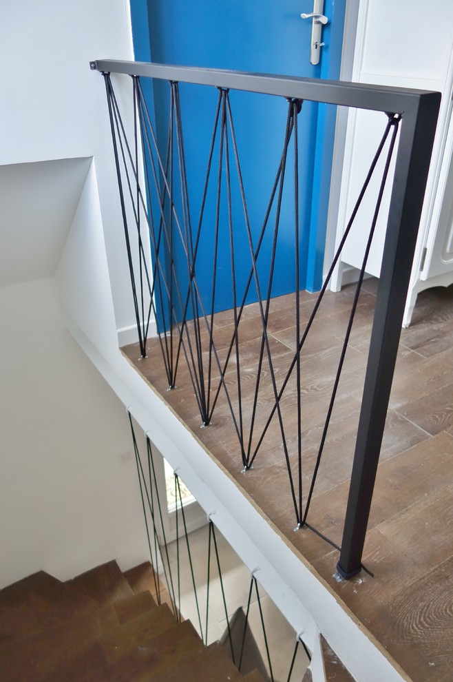This is an example of a contemporary wood u-shaped staircase in Marseille with concrete risers and cable railing.