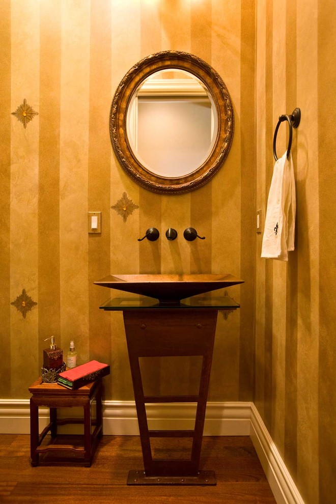 Mid-sized traditional powder room in San Francisco with a vessel sink, furniture-like cabinets, dark wood cabinets, glass benchtops, a one-piece toilet, yellow tile, yellow walls, dark hardwood floors, brown floor and brown benchtops.