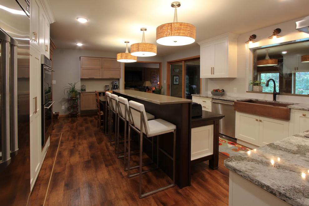Mid-sized transitional l-shaped open concept kitchen photo with a farmhouse sink, beaded inset cabinets, white cabinets, quartzite countertops, white backsplash, stainless steel appliances and an island