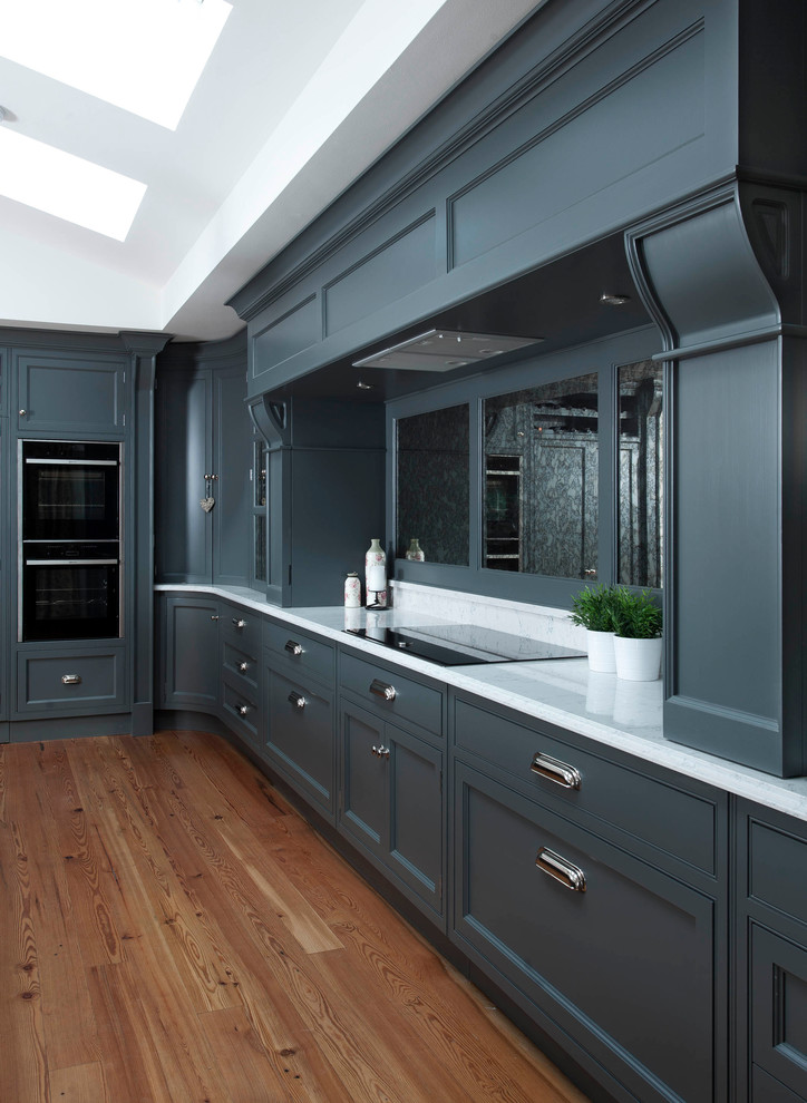 This is an example of a large transitional l-shaped eat-in kitchen in Other with raised-panel cabinets, grey cabinets, quartzite benchtops, mirror splashback, panelled appliances, medium hardwood floors and brown floor.
