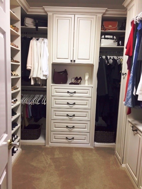 This is an example of a mid-sized traditional gender-neutral walk-in wardrobe in Chicago with raised-panel cabinets, white cabinets, carpet and beige floor.
