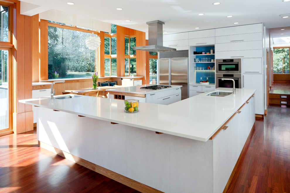 Inspiration for a contemporary l-shaped kitchen in Boston with a double-bowl sink, quartz benchtops, flat-panel cabinets, white cabinets, stainless steel appliances, blue splashback and glass sheet splashback.