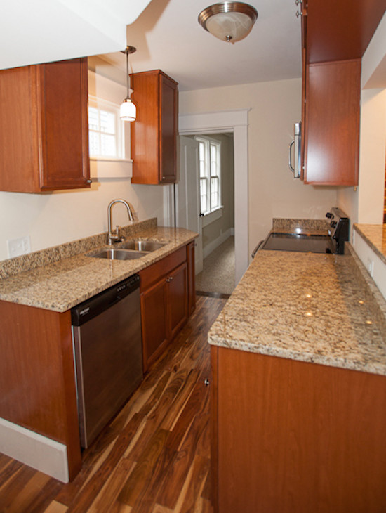 Example of a transitional medium tone wood floor kitchen design in Charleston with an undermount sink, medium tone wood cabinets, granite countertops and stainless steel appliances