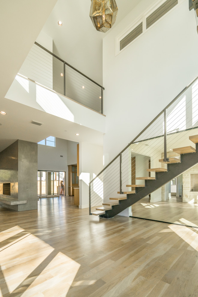 Photo of a large contemporary wood floating mixed railing staircase in Dallas with open risers.